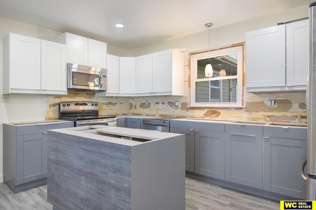 kitchen with appliances with stainless steel finishes, light hardwood / wood-style flooring, and gray cabinetry