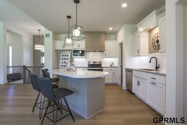 kitchen featuring white cabinetry, appliances with stainless steel finishes, sink, and an island with sink