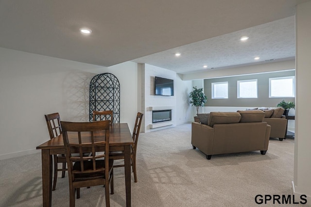 dining area with light carpet, a textured ceiling, and a fireplace