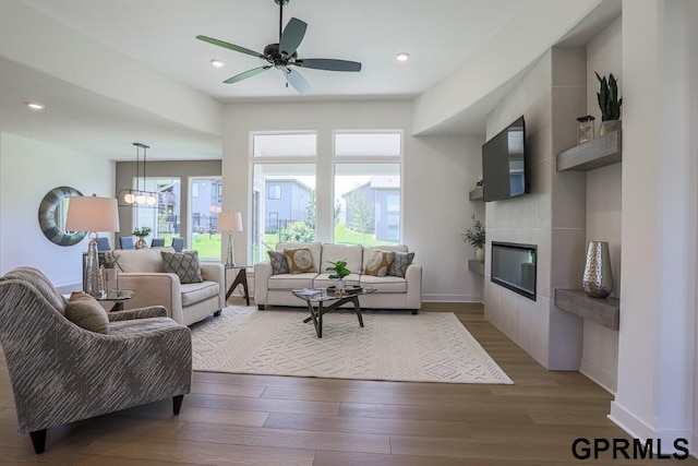 living room featuring a tiled fireplace, hardwood / wood-style floors, and ceiling fan