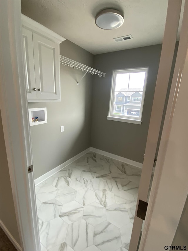 washroom featuring hookup for a washing machine and cabinets