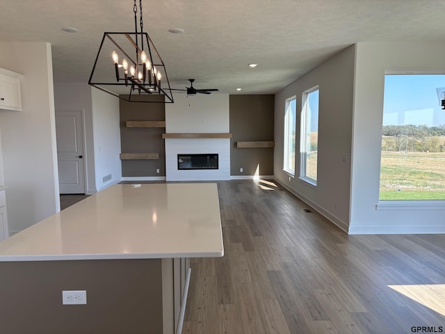 kitchen with a large fireplace, white cabinetry, a kitchen island, and hanging light fixtures