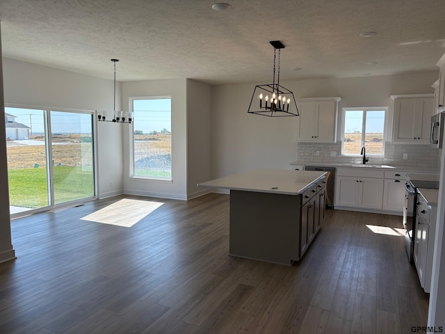 kitchen featuring white cabinets, decorative light fixtures, a center island, and stainless steel appliances