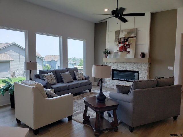 living room featuring ceiling fan, a fireplace, and wood-type flooring