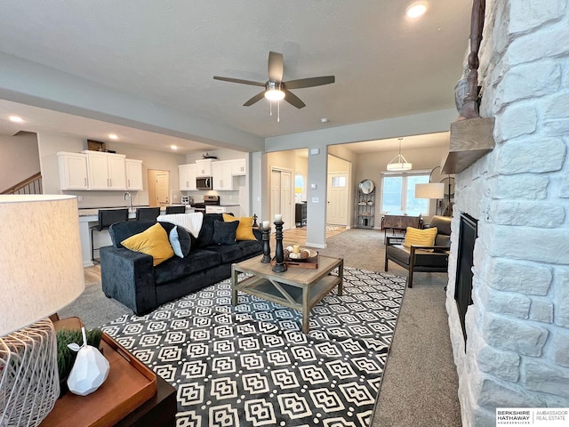 living room with ceiling fan, a fireplace, and light carpet