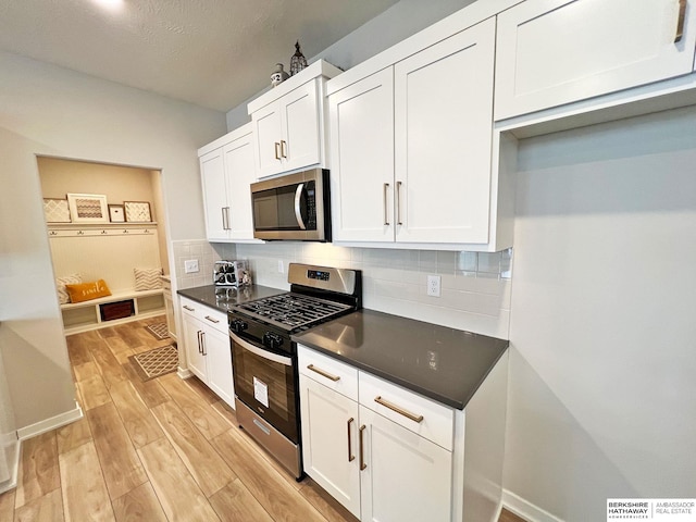 kitchen featuring decorative backsplash, white cabinetry, light hardwood / wood-style floors, and appliances with stainless steel finishes