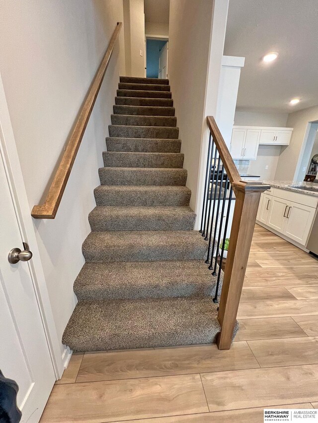 stairs with hardwood / wood-style floors and sink