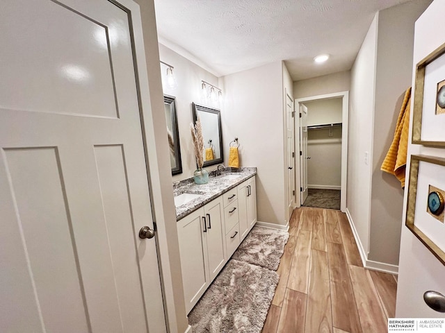 bathroom with hardwood / wood-style floors, vanity, and a textured ceiling