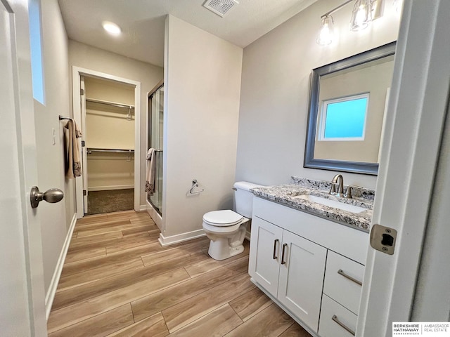 bathroom featuring vanity, toilet, and a shower with shower door