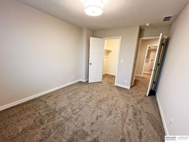 unfurnished bedroom featuring carpet, a spacious closet, and a closet