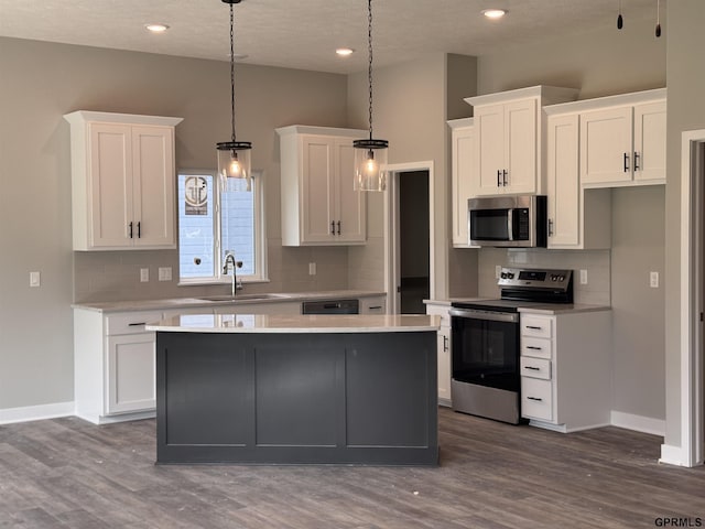 kitchen featuring a center island, sink, hanging light fixtures, white cabinetry, and stainless steel appliances