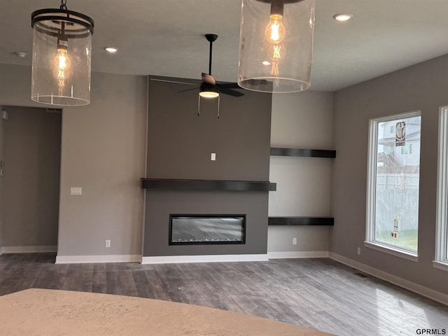 unfurnished living room featuring ceiling fan and hardwood / wood-style flooring