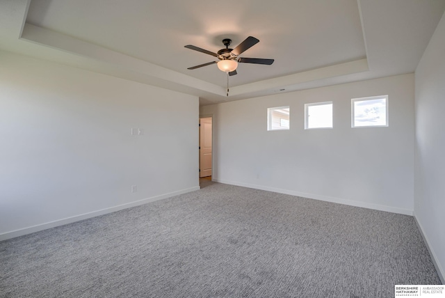 spare room featuring a tray ceiling, ceiling fan, and carpet flooring