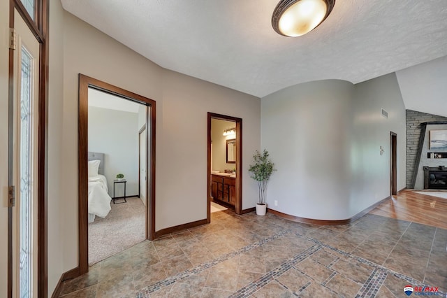 hallway with lofted ceiling and a textured ceiling