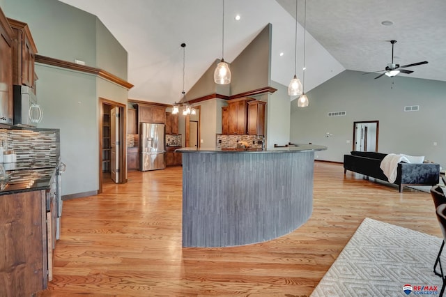 kitchen featuring stainless steel fridge with ice dispenser, decorative backsplash, high vaulted ceiling, and pendant lighting