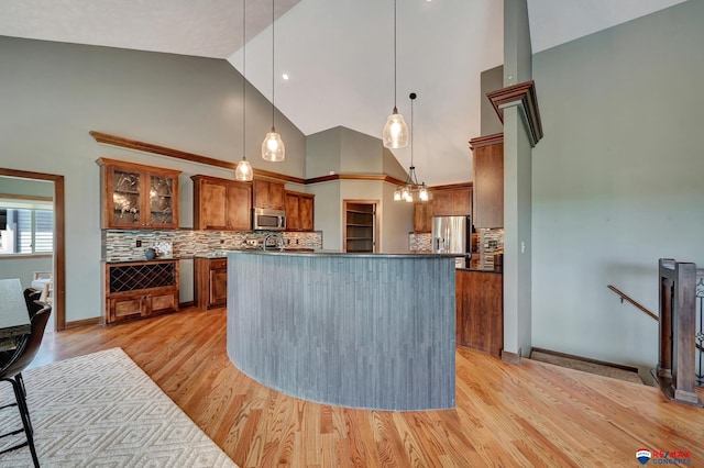 kitchen featuring decorative backsplash, pendant lighting, stainless steel appliances, and high vaulted ceiling