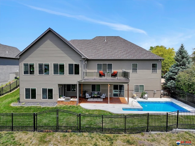 rear view of property with an outdoor hangout area, a balcony, a patio, a yard, and a fenced in pool