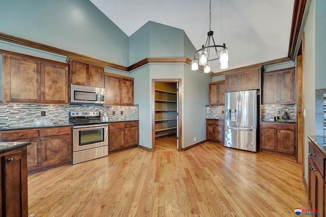 kitchen with pendant lighting, high vaulted ceiling, light wood-type flooring, tasteful backsplash, and stainless steel appliances