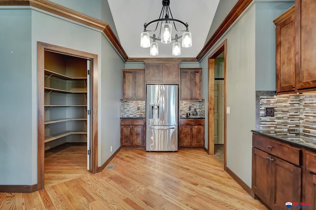 kitchen featuring hanging light fixtures, an inviting chandelier, tasteful backsplash, stainless steel fridge, and ornamental molding