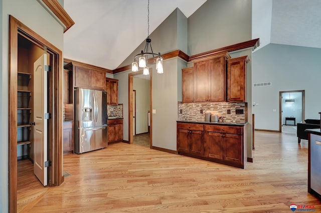 kitchen with stainless steel fridge, backsplash, decorative light fixtures, high vaulted ceiling, and light hardwood / wood-style floors