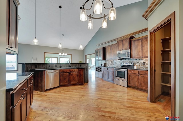 kitchen featuring sink, hanging light fixtures, stainless steel appliances, an inviting chandelier, and backsplash