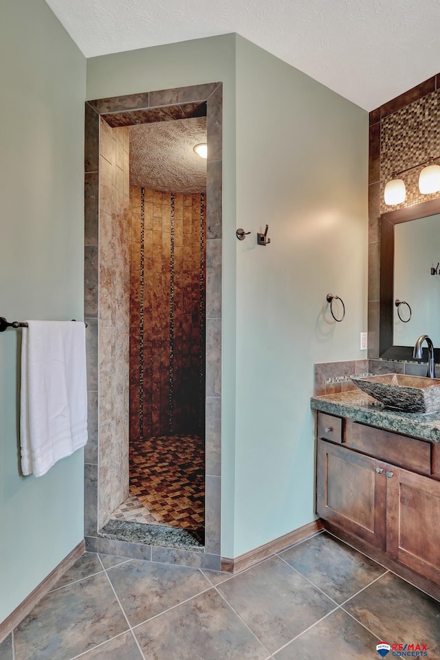 bathroom with tile patterned floors, vanity, and tiled shower