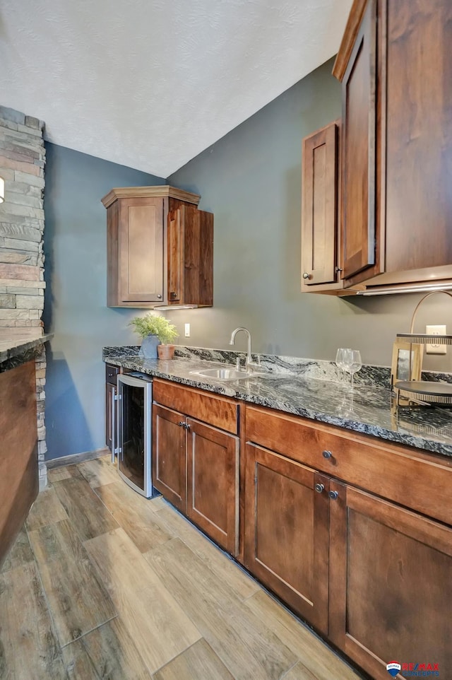 kitchen with dark stone countertops, sink, and beverage cooler