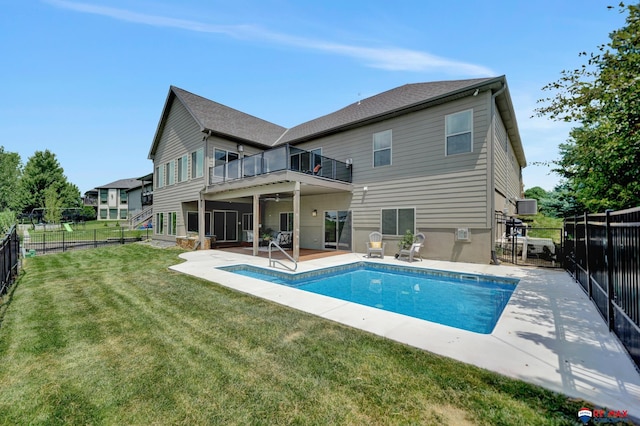 back of property featuring a balcony, a fenced in pool, a patio, and a yard