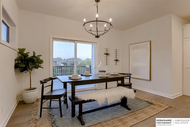 dining space with hardwood / wood-style floors and a notable chandelier