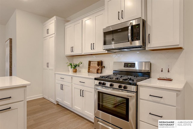 kitchen with light hardwood / wood-style floors, white cabinetry, stainless steel appliances, and tasteful backsplash