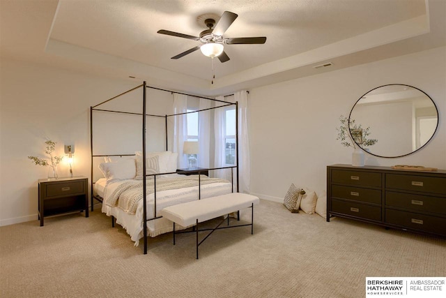 carpeted bedroom featuring a raised ceiling and ceiling fan