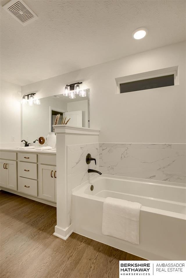 bathroom featuring a tub to relax in, vanity, and hardwood / wood-style flooring