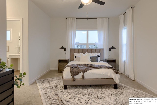 carpeted bedroom with ensuite bath and ceiling fan