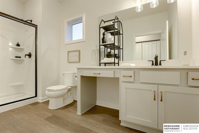 bathroom with hardwood / wood-style floors, vanity, toilet, and a shower with shower door