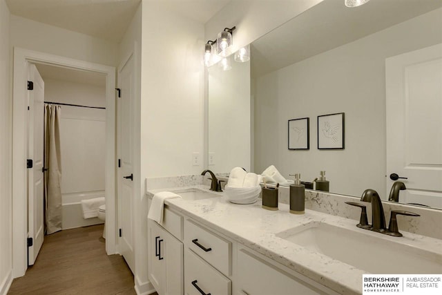 full bathroom with shower / bath combo, vanity, hardwood / wood-style flooring, and toilet