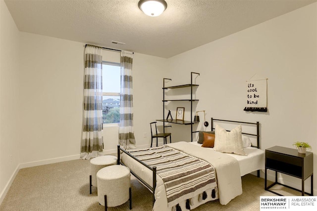 bedroom with light colored carpet and a textured ceiling