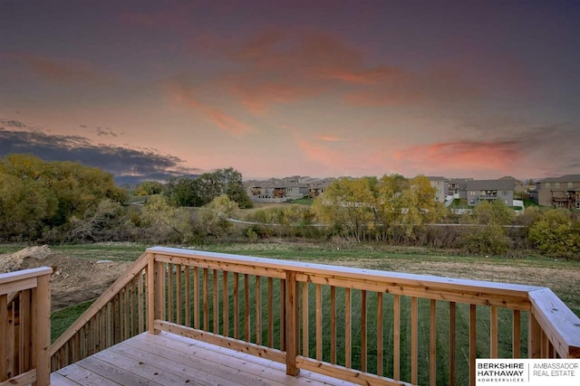 deck at dusk featuring a lawn