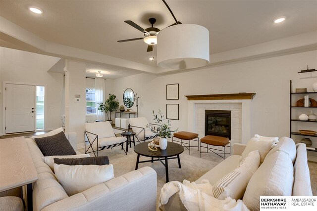 living room with ceiling fan and a tile fireplace