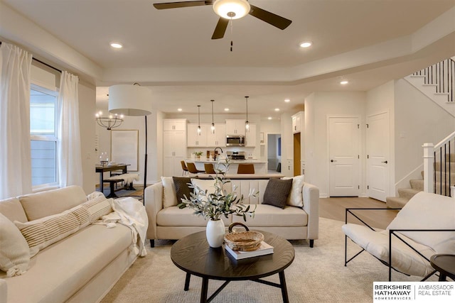 living room featuring sink and ceiling fan with notable chandelier