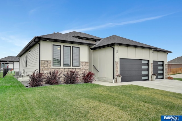 prairie-style house featuring central AC unit, a garage, and a front yard