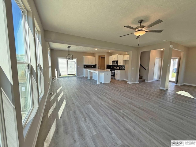 unfurnished living room with ceiling fan, light hardwood / wood-style floors, and a textured ceiling