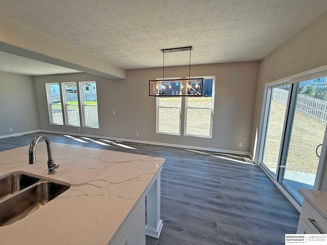 kitchen featuring white cabinets, decorative light fixtures, sink, and a textured ceiling