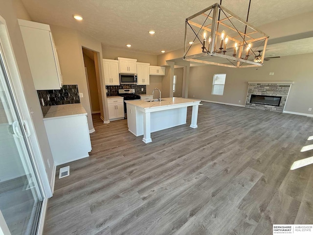 kitchen featuring white cabinets, appliances with stainless steel finishes, pendant lighting, and wood-type flooring