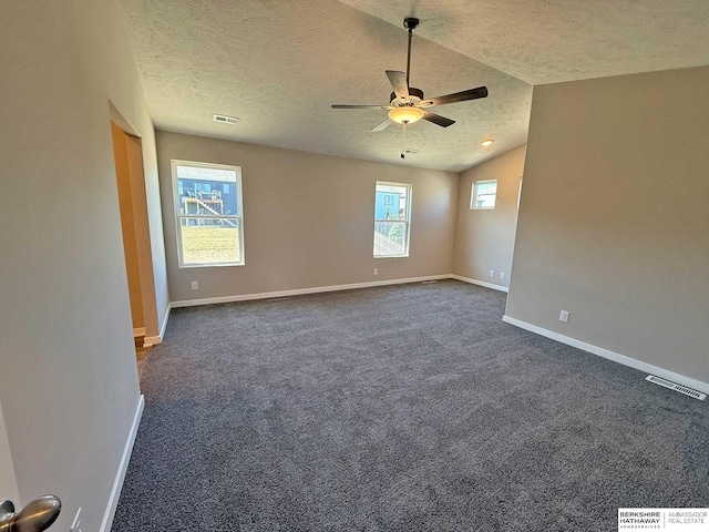 unfurnished room featuring a textured ceiling, ceiling fan, vaulted ceiling, and dark colored carpet