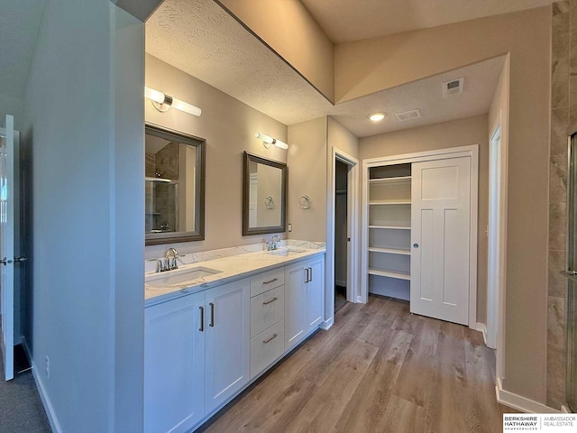 bathroom with hardwood / wood-style floors, vanity, a textured ceiling, and a shower with shower door