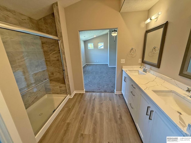 bathroom with lofted ceiling, wood-type flooring, a textured ceiling, and walk in shower