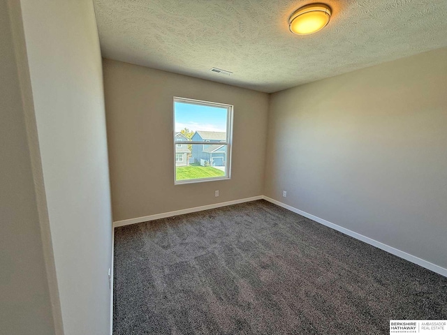 spare room with dark colored carpet and a textured ceiling