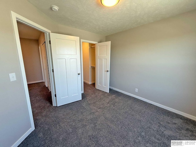 unfurnished bedroom with a closet, dark carpet, and a textured ceiling