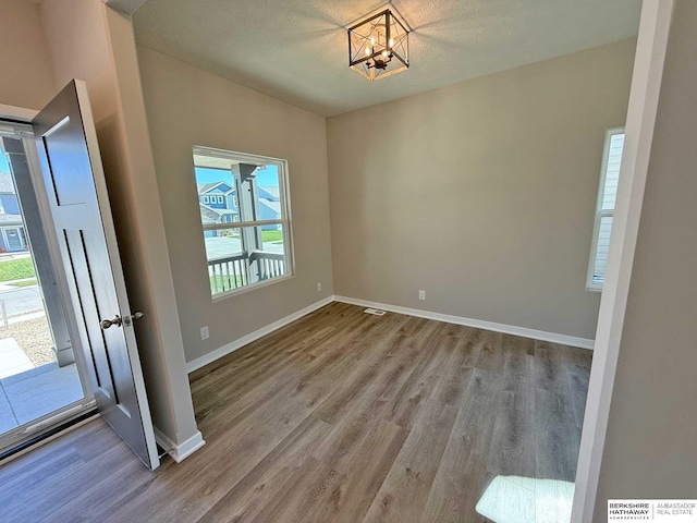 unfurnished dining area with a chandelier, light hardwood / wood-style floors, and a textured ceiling