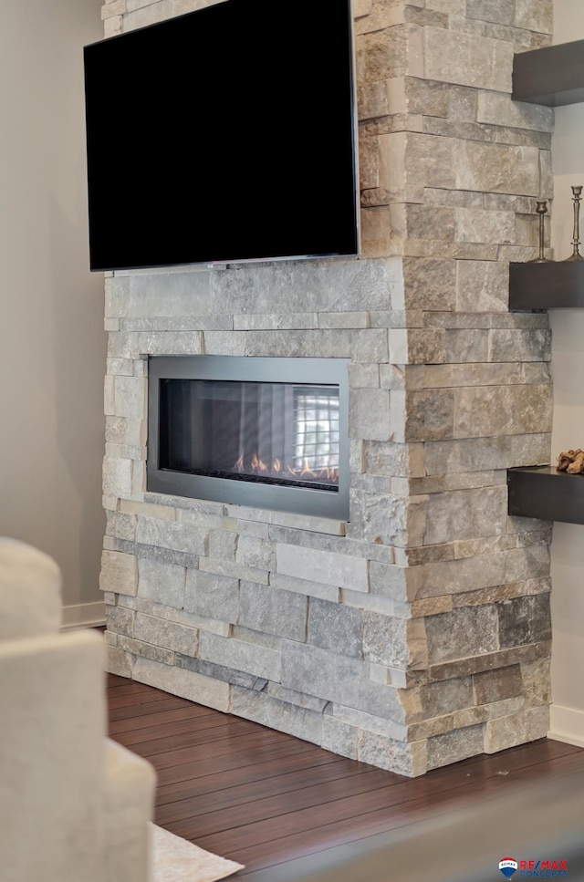 room details with hardwood / wood-style floors and a stone fireplace